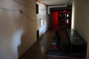 A dark hallway with red light in the distance.