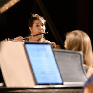 A person playing a flute behind a tablet screen.