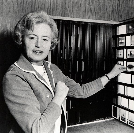 A black and white image of a person pointing to small astronomical images.